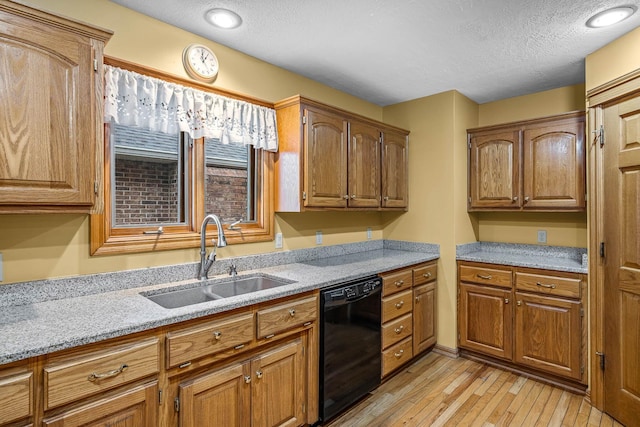 kitchen with sink, dishwasher, light stone counters, light hardwood / wood-style floors, and a textured ceiling