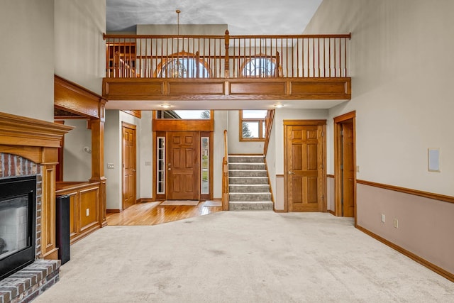 unfurnished living room with a brick fireplace, light carpet, and a high ceiling