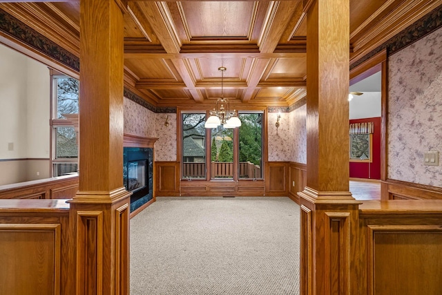 unfurnished living room featuring wood ceiling, carpet, coffered ceiling, ornamental molding, and a chandelier