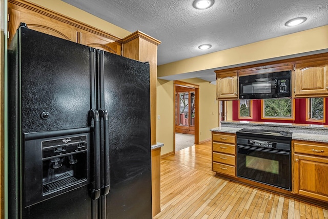 kitchen with a textured ceiling, light hardwood / wood-style floors, and black appliances