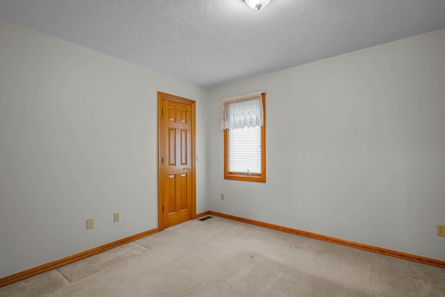 unfurnished room featuring light carpet and a textured ceiling