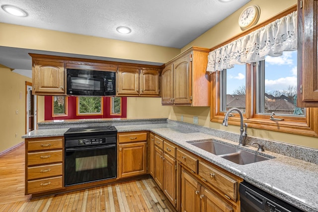 kitchen with sink, light hardwood / wood-style flooring, black appliances, and a textured ceiling