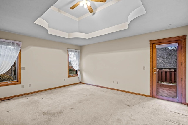 unfurnished room with ceiling fan, carpet flooring, and a raised ceiling