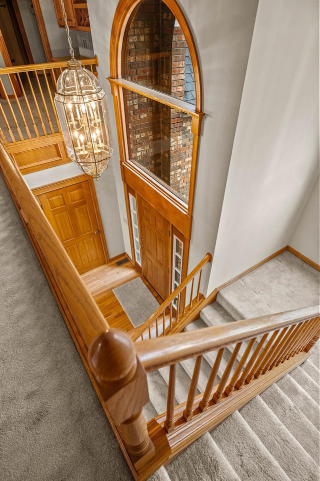 stairway with a chandelier and carpet floors