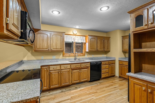 kitchen featuring sink, light stone counters, a textured ceiling, light hardwood / wood-style floors, and black appliances