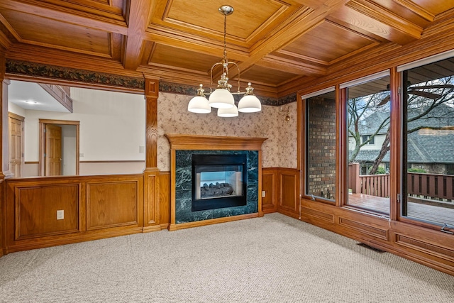 unfurnished living room featuring coffered ceiling, wood ceiling, a high end fireplace, and light colored carpet