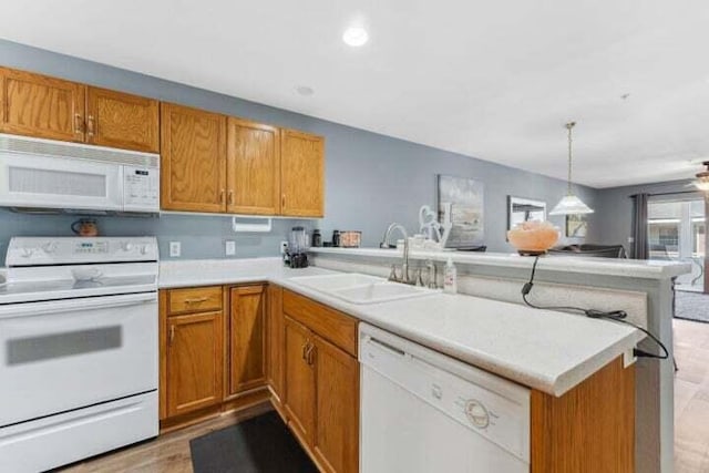 kitchen with white appliances, decorative light fixtures, kitchen peninsula, and sink