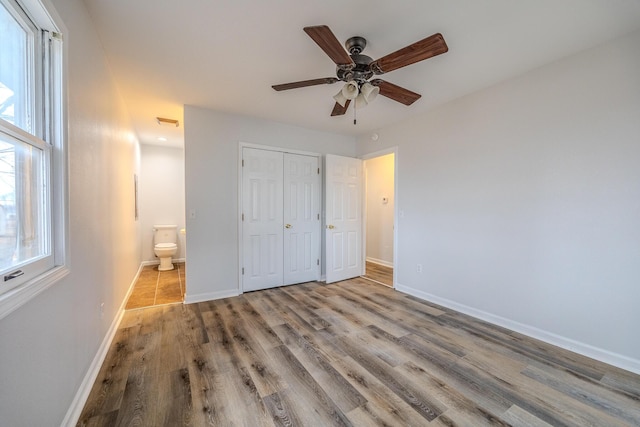 unfurnished bedroom featuring multiple windows, a closet, ensuite bathroom, and light hardwood / wood-style flooring