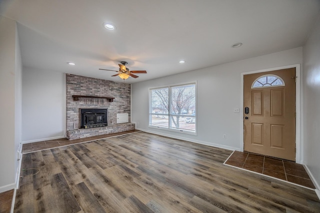 unfurnished living room with a brick fireplace, dark hardwood / wood-style floors, and ceiling fan