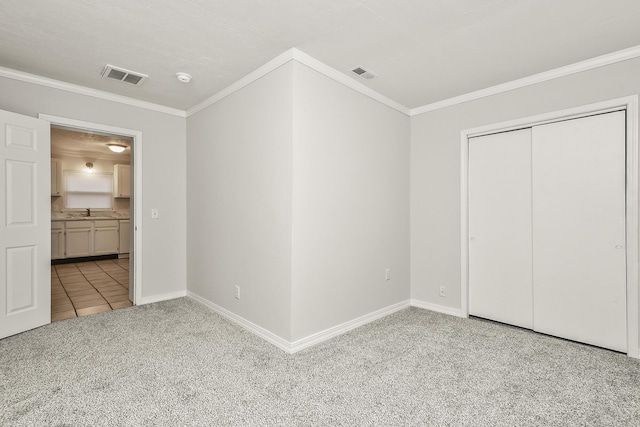 unfurnished bedroom with light carpet, sink, ornamental molding, and a closet