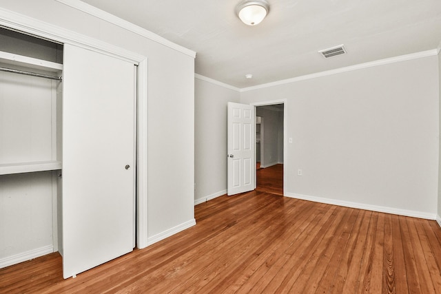 unfurnished bedroom featuring crown molding, a closet, and light hardwood / wood-style flooring