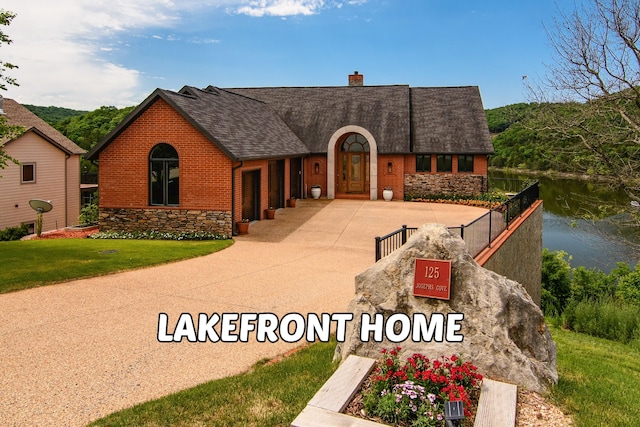 view of front of home with a water view and a front lawn