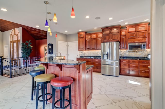 kitchen with a kitchen island, appliances with stainless steel finishes, pendant lighting, a breakfast bar area, and backsplash