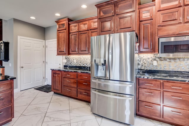 kitchen with appliances with stainless steel finishes, decorative backsplash, and dark stone counters