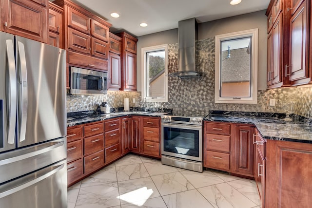 kitchen featuring appliances with stainless steel finishes, wall chimney range hood, decorative backsplash, and dark stone counters