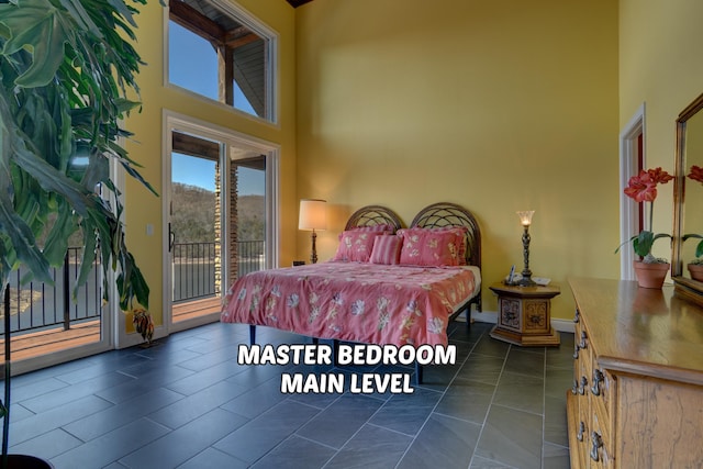 bedroom featuring a towering ceiling, dark tile patterned floors, and access to outside