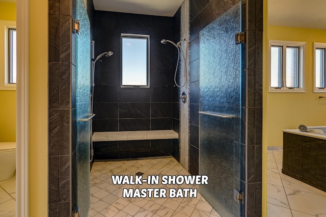 bathroom featuring a wealth of natural light, a shower with shower door, and toilet