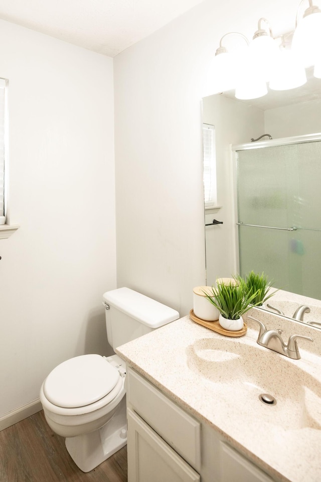 bathroom featuring vanity, hardwood / wood-style floors, an enclosed shower, and toilet