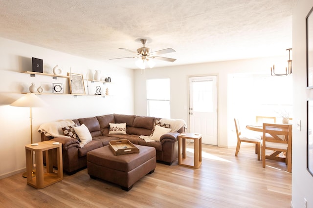 living room featuring ceiling fan, light hardwood / wood-style flooring, and a textured ceiling