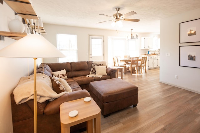 living room featuring ceiling fan, a textured ceiling, and light hardwood / wood-style flooring