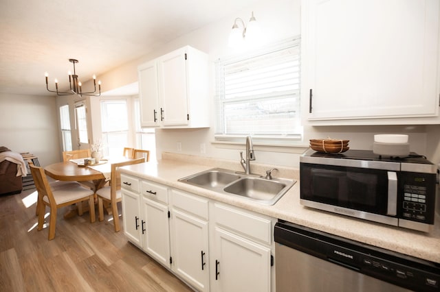 kitchen featuring pendant lighting, sink, white cabinets, stainless steel appliances, and light hardwood / wood-style flooring