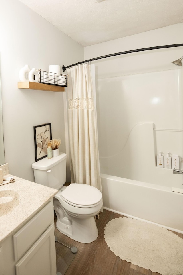 full bathroom with hardwood / wood-style flooring, vanity, shower / bath combo with shower curtain, and toilet