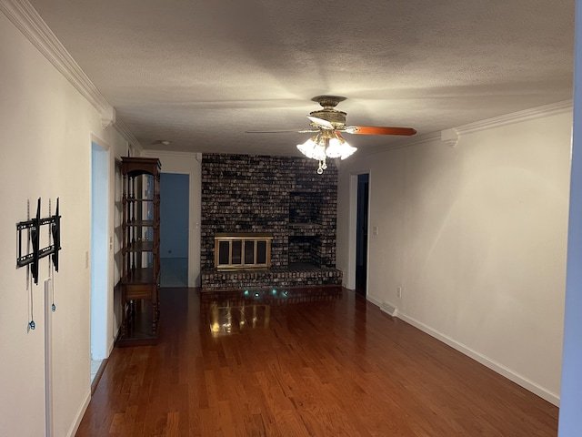 unfurnished living room featuring a brick fireplace, crown molding, dark wood-type flooring, and a textured ceiling