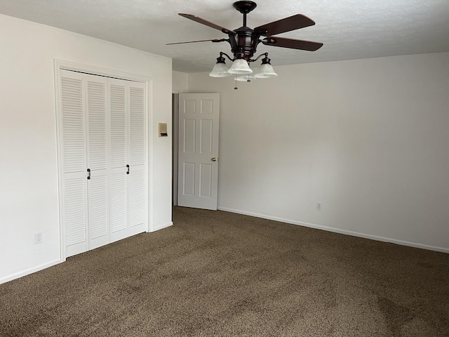 unfurnished bedroom with ceiling fan, dark carpet, a closet, and a textured ceiling