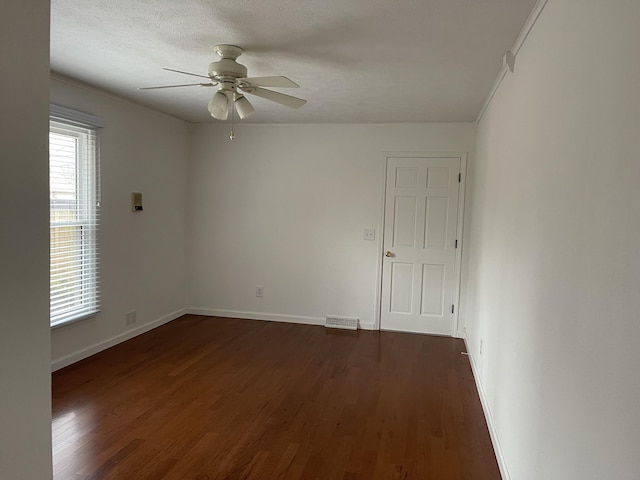 unfurnished room featuring a textured ceiling, dark wood-style flooring, visible vents, a ceiling fan, and baseboards