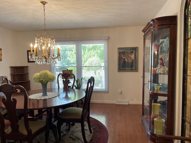 dining area with dark wood-style floors, a notable chandelier, visible vents, and baseboards