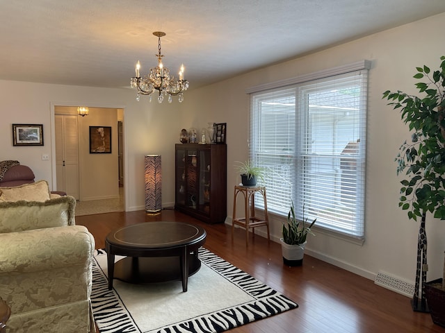 living area with dark wood-style floors, a chandelier, visible vents, and baseboards