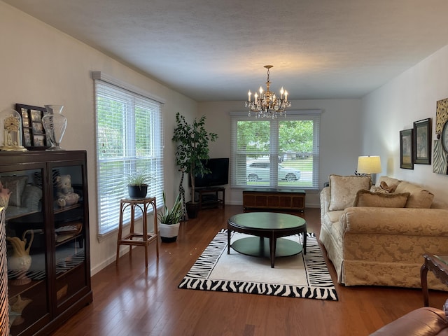 living area with a chandelier, dark wood-style flooring, and baseboards