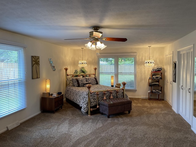 bedroom with visible vents, ceiling fan, dark colored carpet, a textured ceiling, and two closets