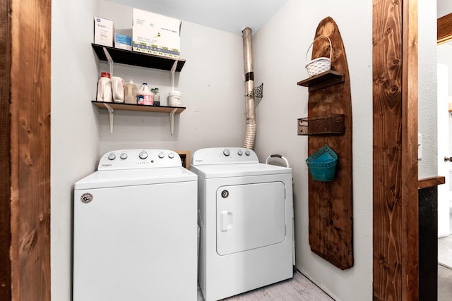 laundry room with washing machine and clothes dryer and light wood-type flooring