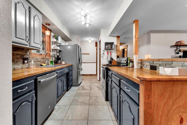 kitchen with appliances with stainless steel finishes, butcher block countertops, sink, backsplash, and light tile patterned floors