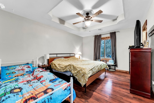 bedroom featuring dark hardwood / wood-style floors, ceiling fan, and a tray ceiling