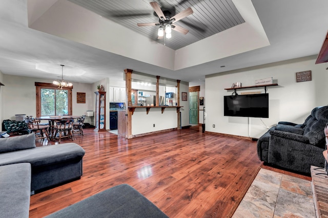 living room with bar, hardwood / wood-style flooring, ceiling fan with notable chandelier, and a raised ceiling