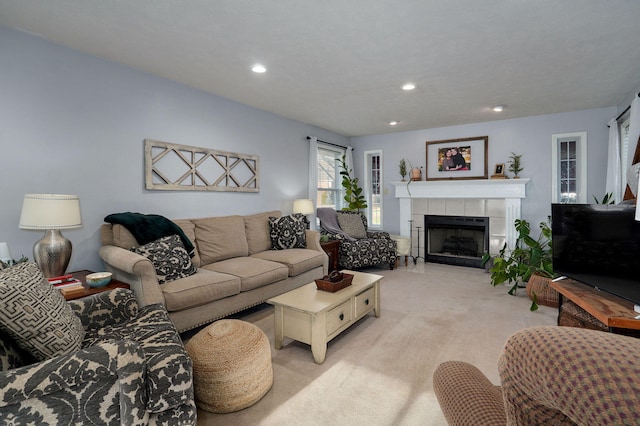 living room featuring a tiled fireplace and light colored carpet