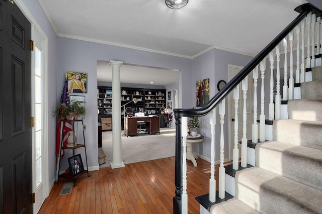 foyer entrance with crown molding, wood-type flooring, and ornate columns