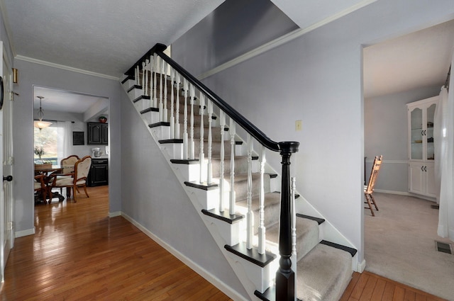 stairs featuring hardwood / wood-style flooring and ornamental molding