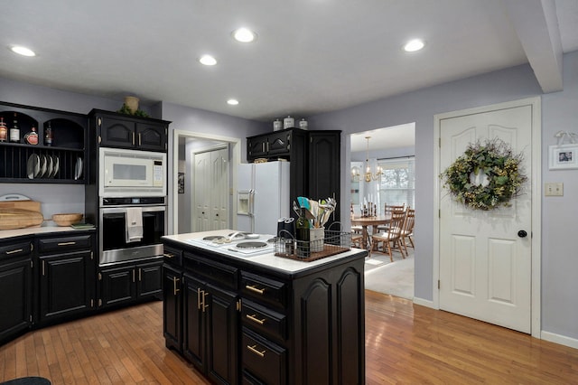 kitchen featuring white appliances, a chandelier, a kitchen island, and light wood-type flooring