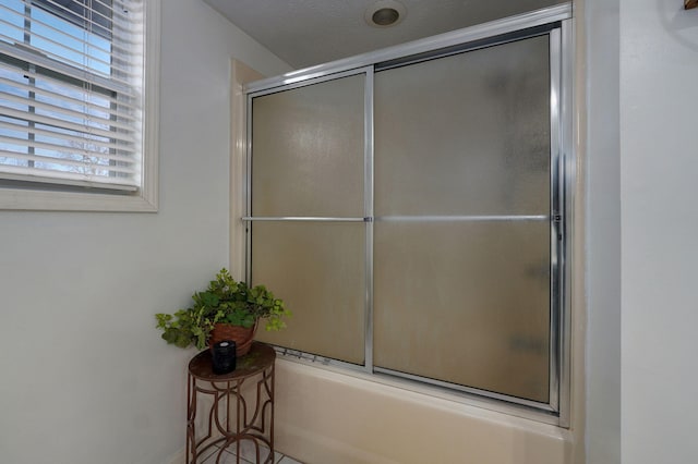 bathroom featuring combined bath / shower with glass door