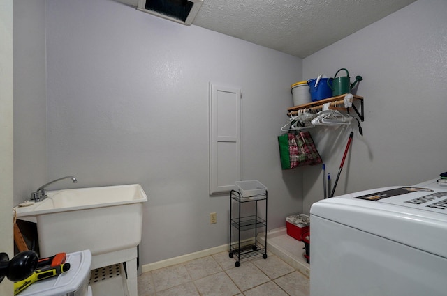 washroom featuring washer / clothes dryer, light tile patterned floors, sink, and a textured ceiling