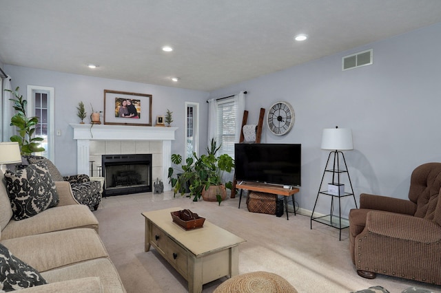 carpeted living room featuring a tiled fireplace