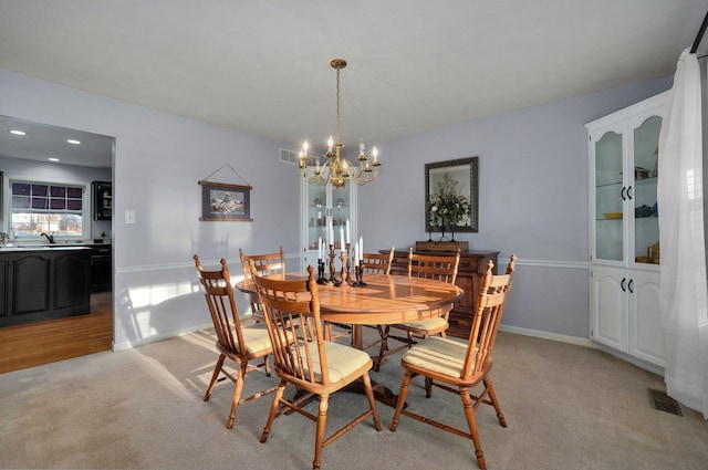 dining space featuring an inviting chandelier, sink, and light carpet