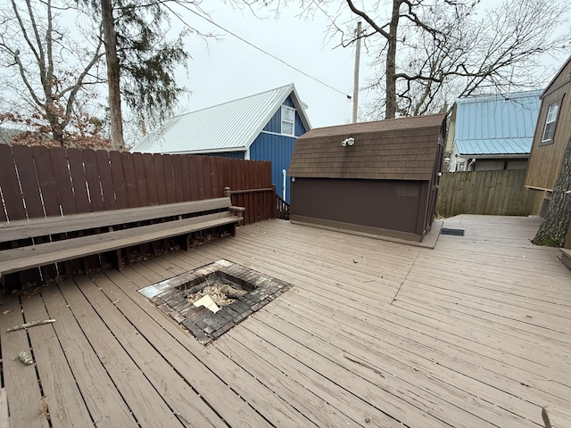 wooden terrace with a storage unit and a fire pit