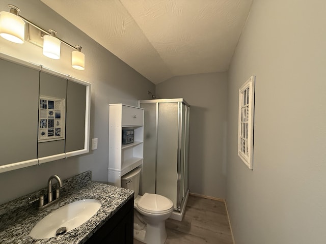 bathroom featuring wood-type flooring, lofted ceiling, vanity, an enclosed shower, and toilet