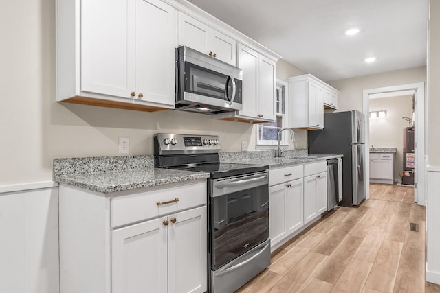 kitchen with white cabinetry, appliances with stainless steel finishes, sink, and light stone counters