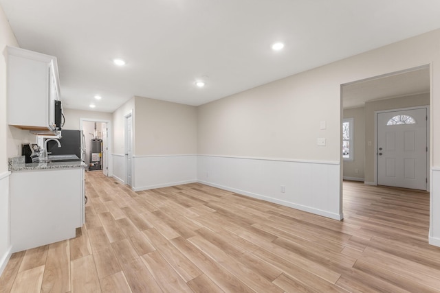 kitchen featuring light stone counters, sink, light hardwood / wood-style flooring, and white cabinets