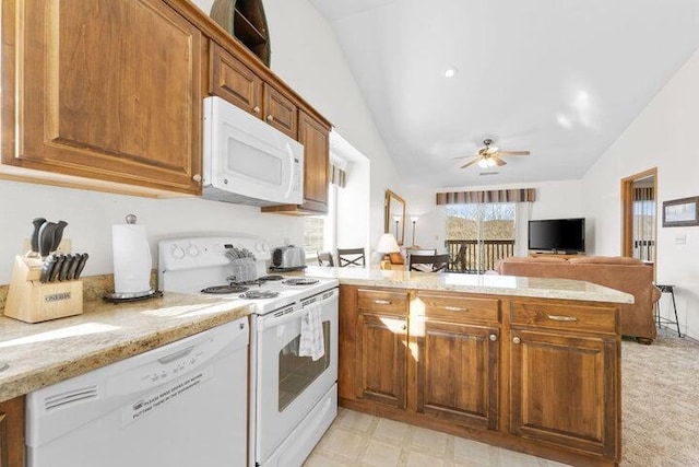 kitchen with lofted ceiling, white appliances, ceiling fan, light stone countertops, and kitchen peninsula